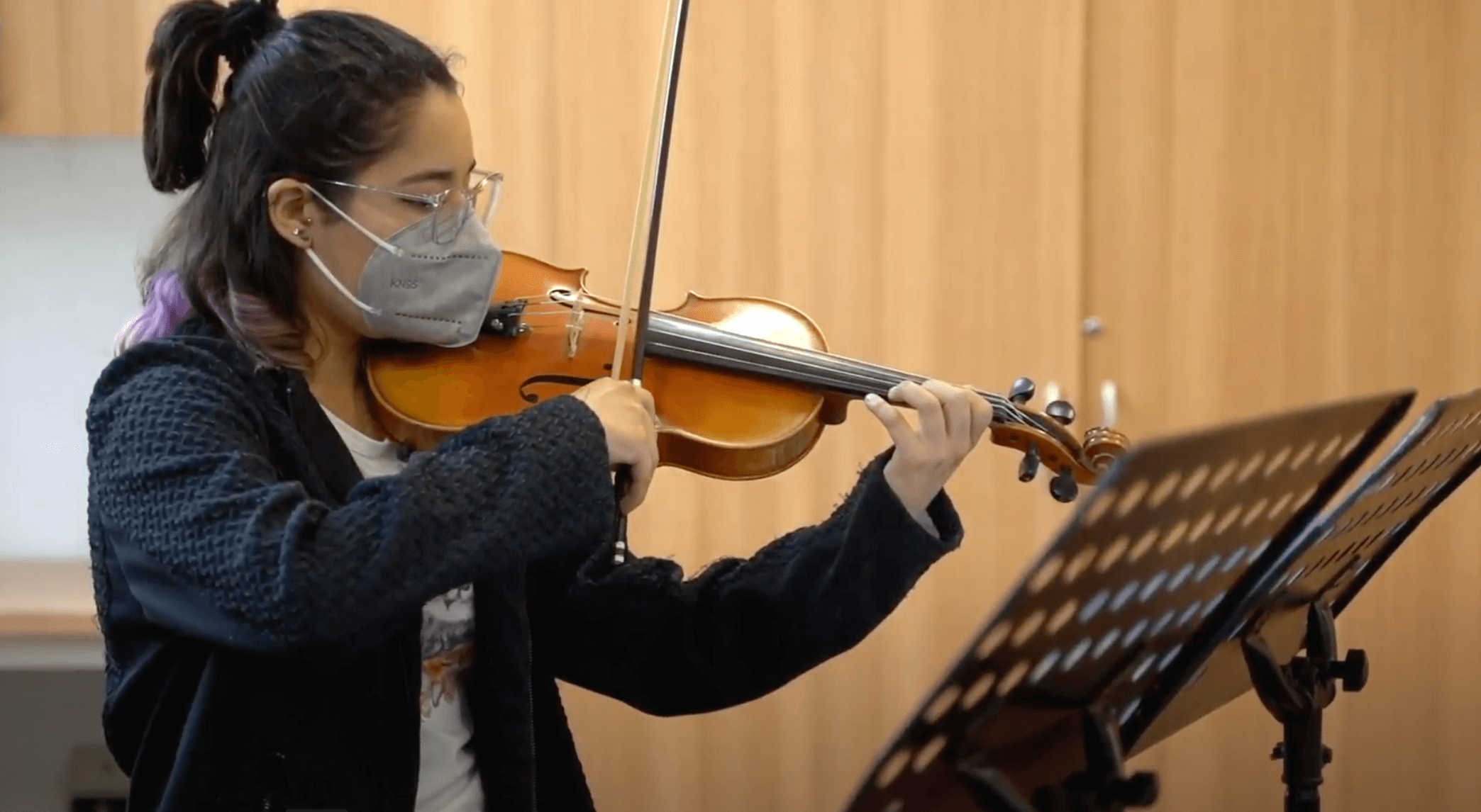 Chica con mascarilla tocando el violín.