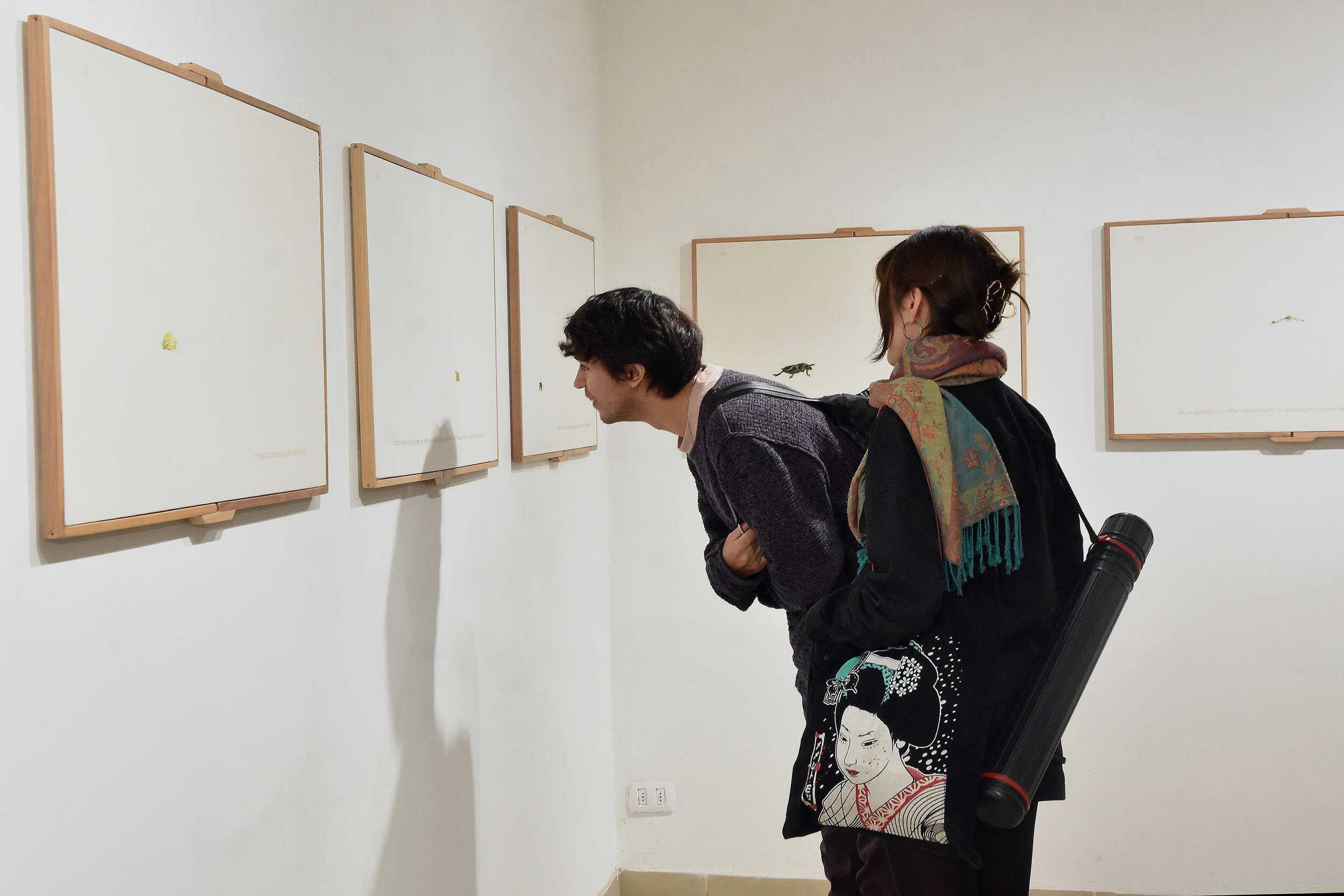 Dos jóvenes mirando cuadros expuestos en una pared